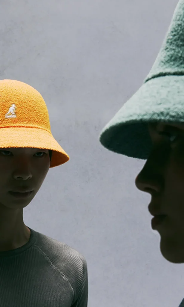 Two models wearing Kangol textured bucket hats, one yellow and one green.