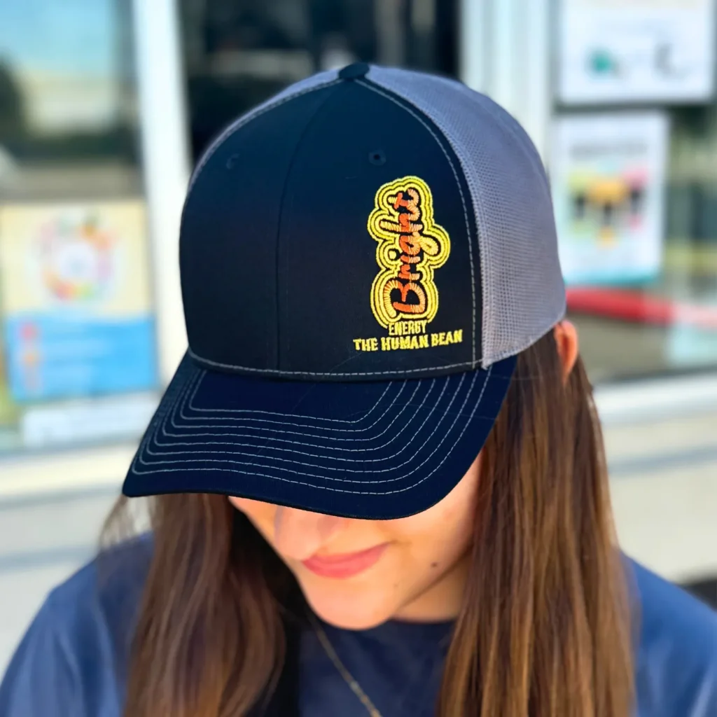 Navy gray trucker hat with bright embroidered logo worn by woman