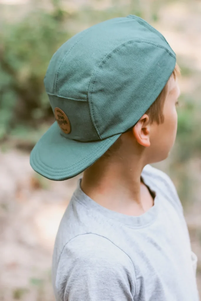Child wearing green five-panel cap outdoors