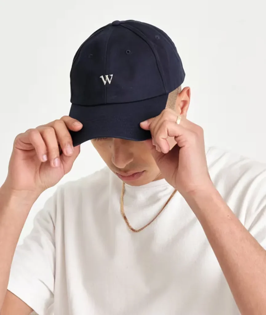 Man wearing navy cap with white "W" logo adjusting the brim.