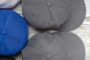 Blue and gray wool baseball caps on wooden surface