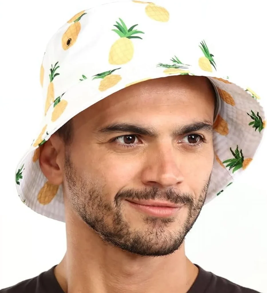 Man wearing white bucket hat with pineapple design, smiling.