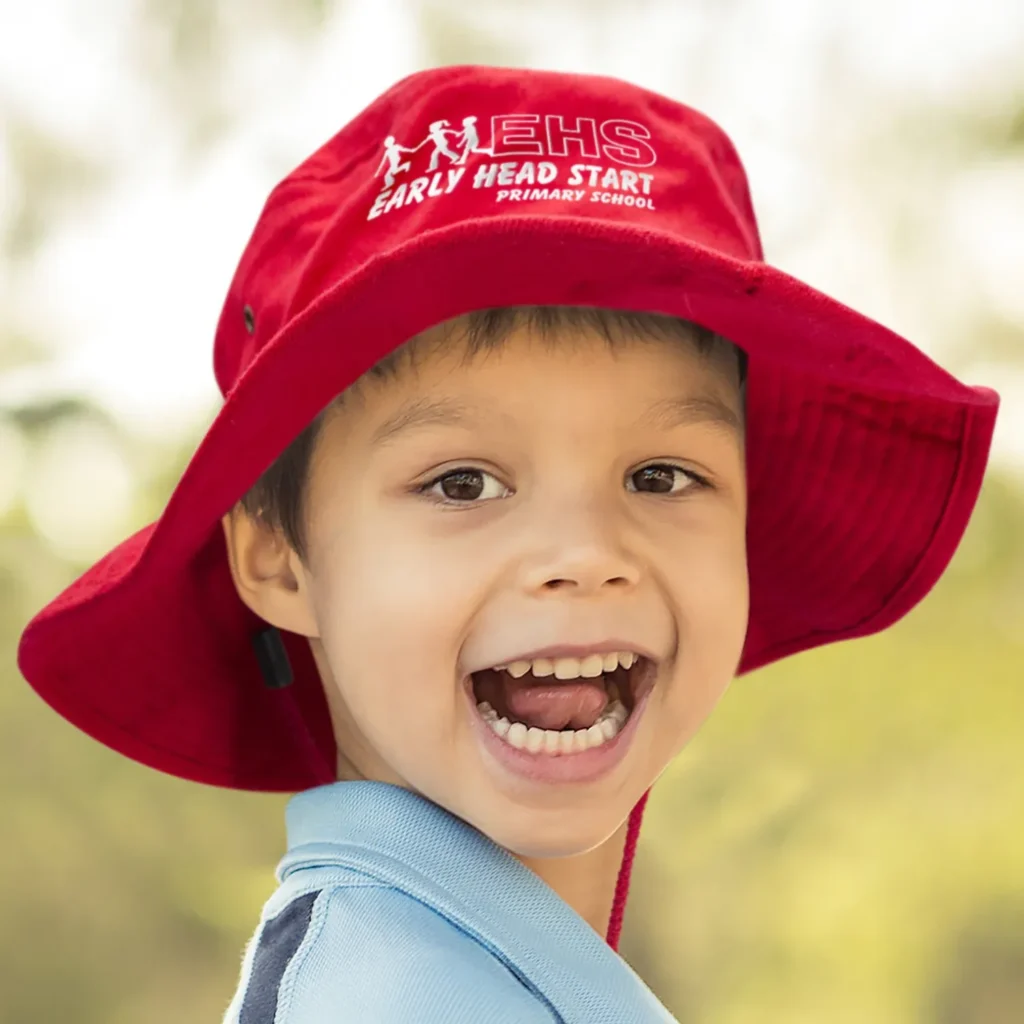 Smiling child wearing red bucket hat outdoors