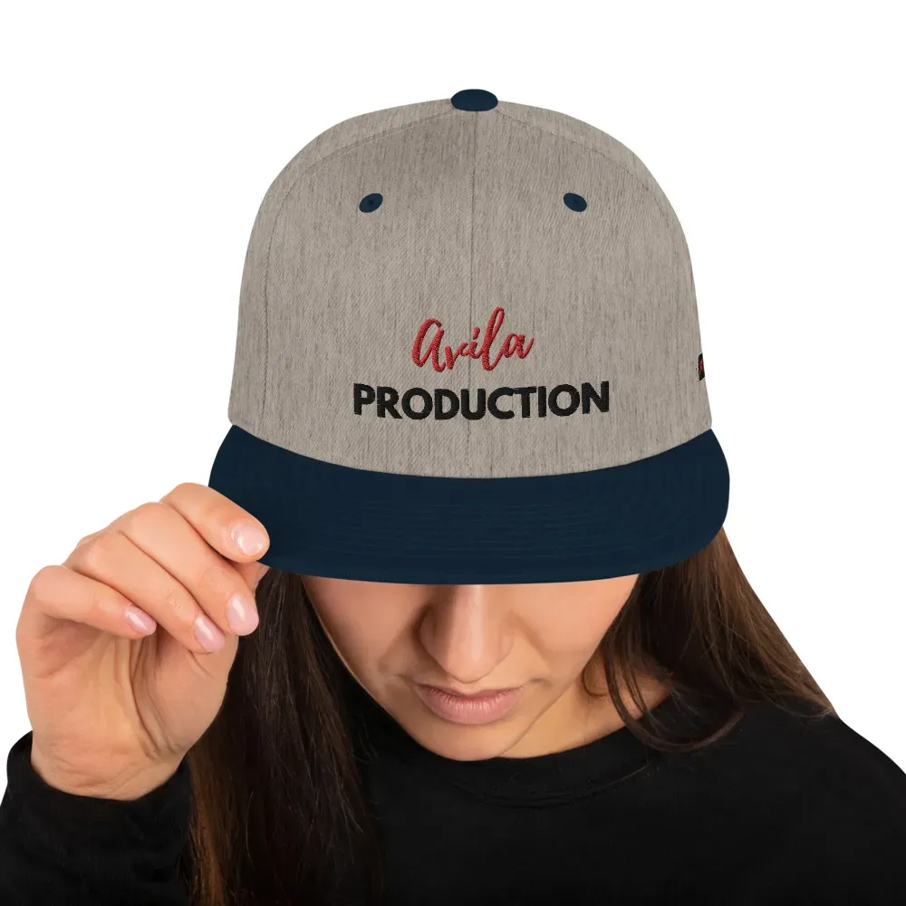 Heather grey and navy snapback with embroidery, worn by woman adjusting brim.