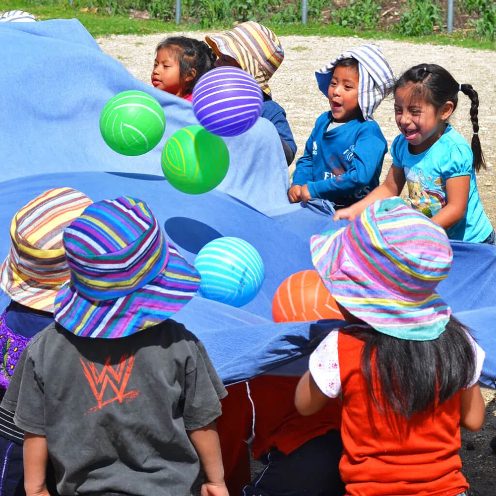 Children playing outside wearing colorful bucket hats with balls