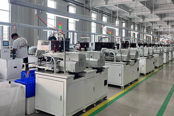 Row of automated sewing machines operating in modern factory.
