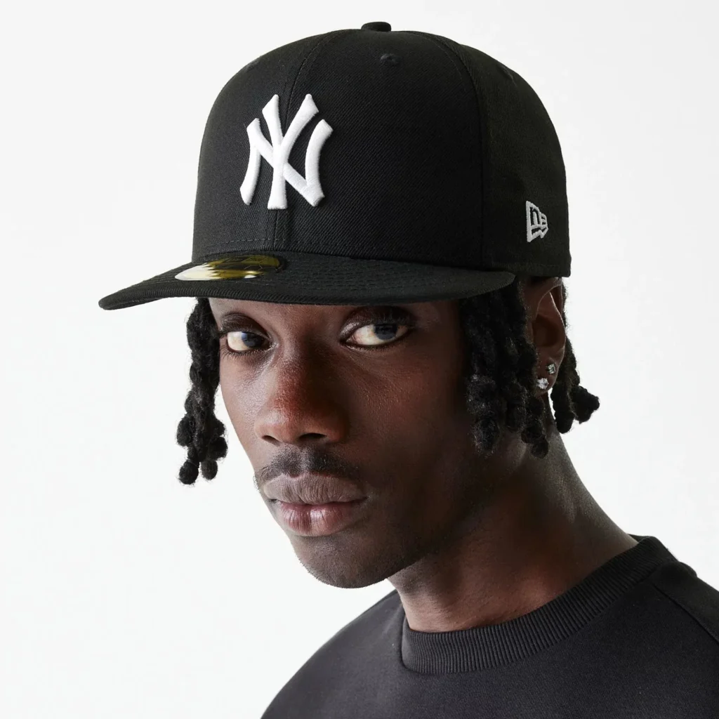 Man wearing black New York Yankees cap looking sideways.