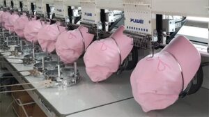 Pink caps being embroidered on industrial embroidery machines.