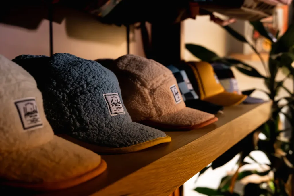 Sherpa fabric baseball caps in various colors displayed on a wooden shelf.