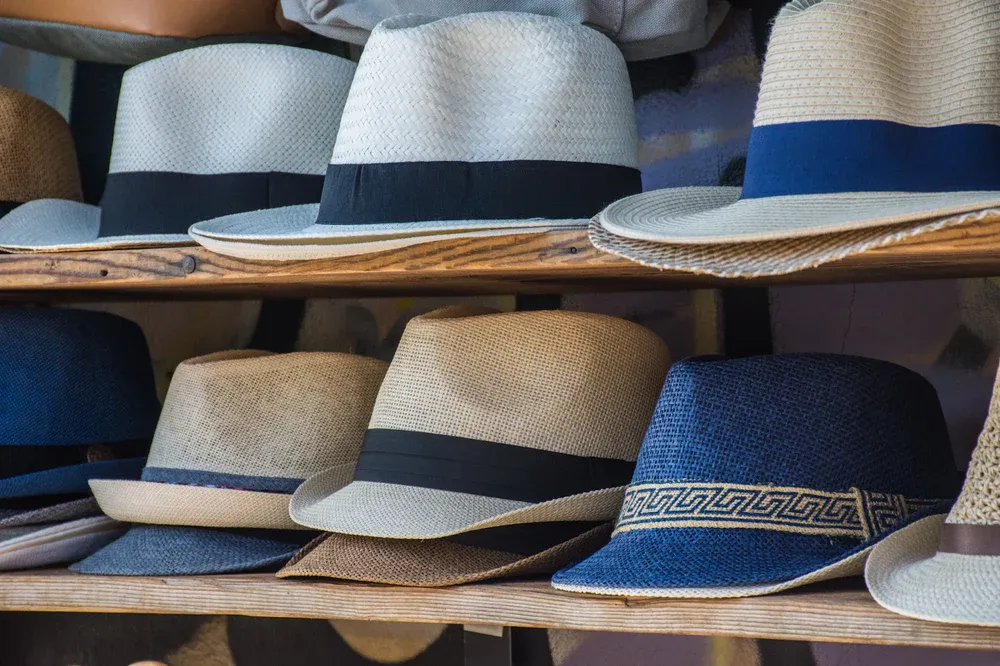 Different styles of straw hats displayed on wooden shelves.