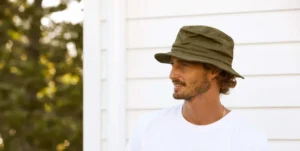 Man with beard wearing olive green bucket hat outdoors.