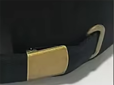 Close-up of black cap strap with gold metal buckle for size adjustment.