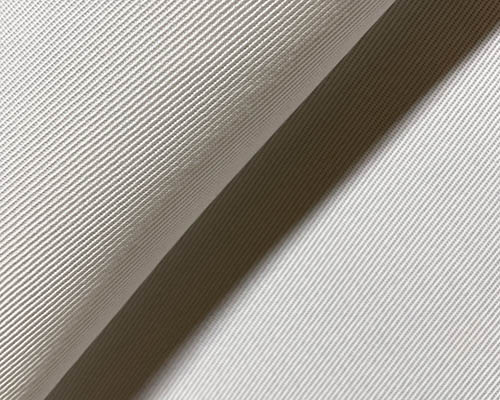 Close-up of beige twill fabric with diagonal weave texture.