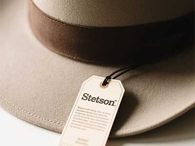 Close-up of beige Stetson hat with detailed brand tag attached.