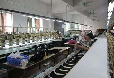 Workers sewing and assembling hats on factory production line.