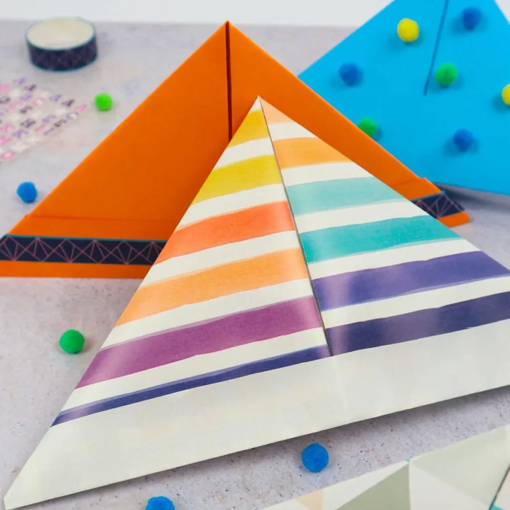 Colorful striped paper hats folded and displayed on a table with craft decorations