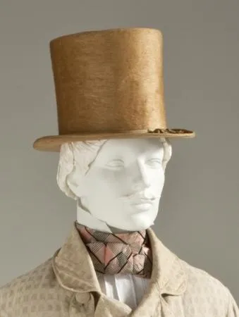 Mannequin wearing vintage gold top hat and patterned scarf in historical attire.