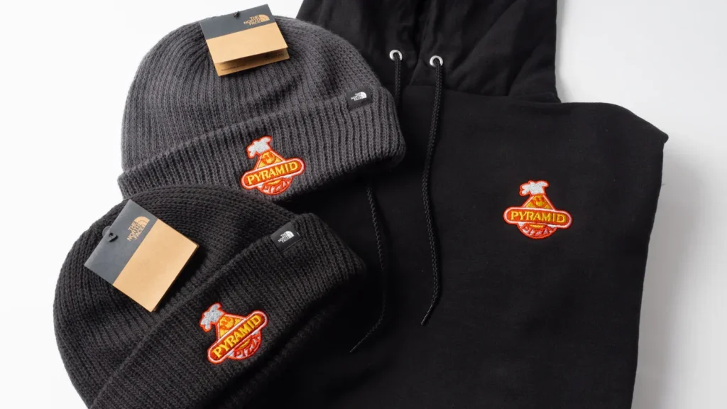 Black beanies and hoodie with colorful embroidered pizza logo.