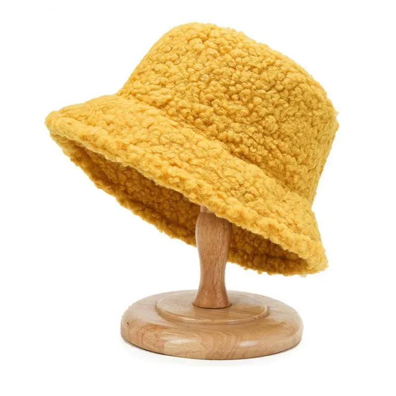 Yellow fleece bucket hat displayed on a wooden stand.