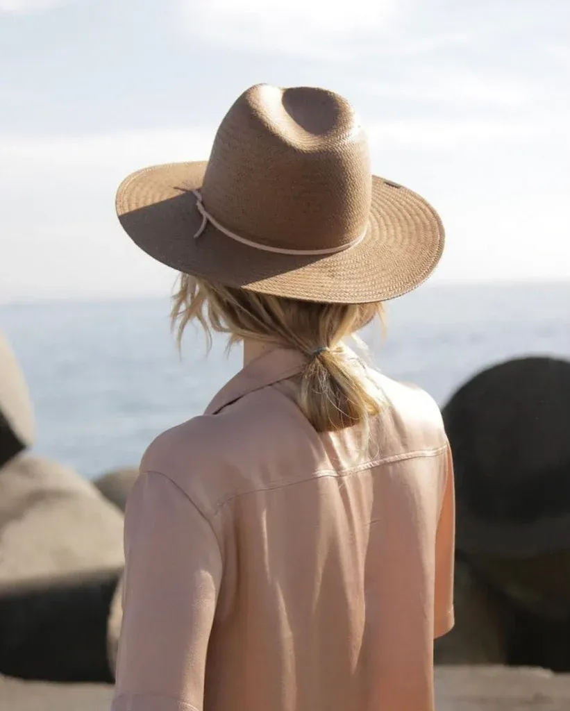 Woman with ponytail wearing a straw hat by the sea