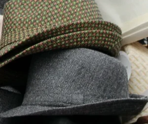 Two wool blend hats stacked with patterned and herringbone fabric